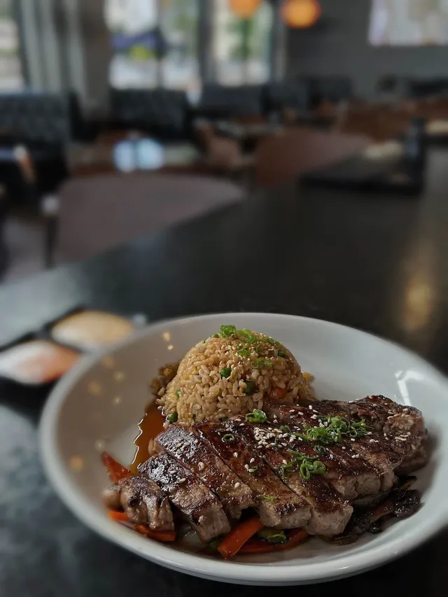 Sliced ribeye over fried rice with vegetables and sesame