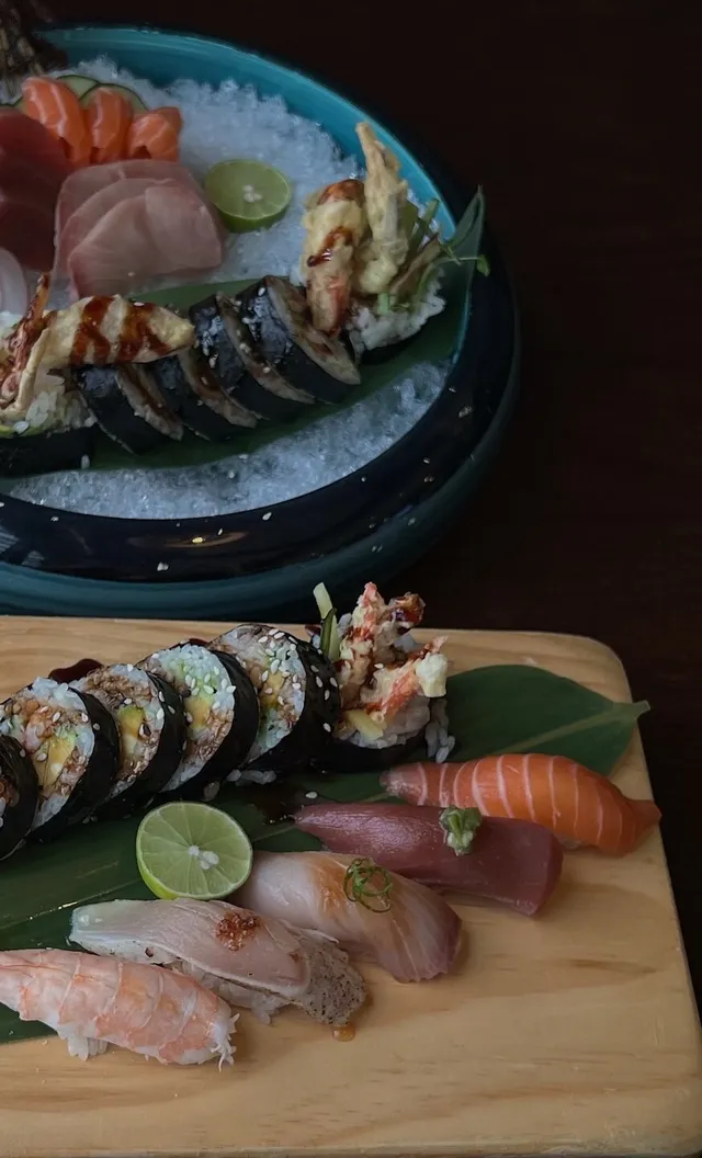 Sushi and sashimi served on ice above maki rolls and nigiri on a wooden board
