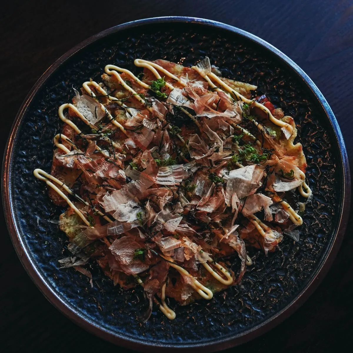 Okonomiyaki topped with bonito flakes, aonori and Japanese mayonnaise