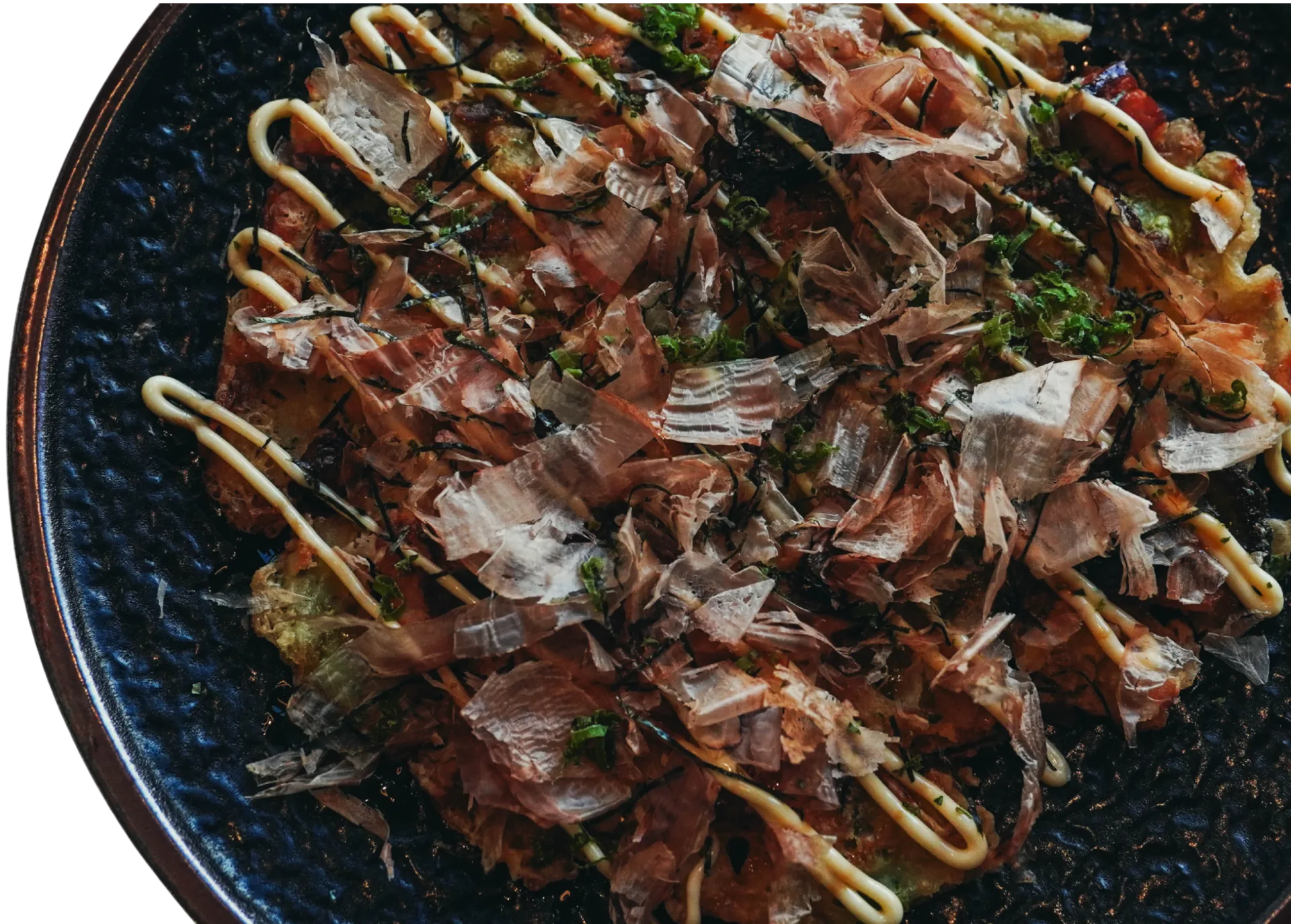 Okonomiyaki topped with bonito flakes, aonori and Japanese mayonnaise